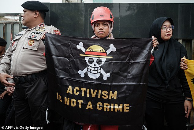 A member of Greenpeace Indonesia holds the pirate flag in a protest against a coastal development