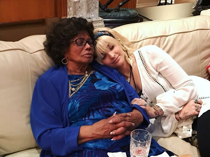 Paris Jackson resting on woman in blue, highlighting family turmoil over Michael Jackson estate claims.