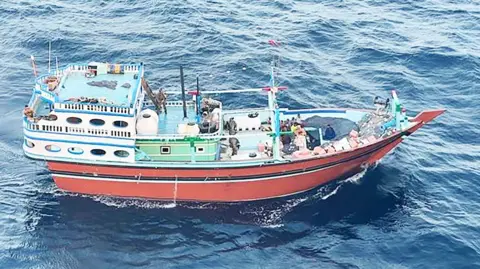 US Department of Justice A colourful fishing boat surrounded by choppy sea.