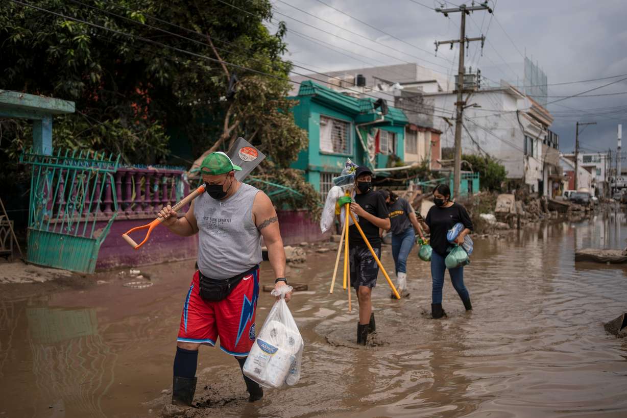 Locals transport supplies along a mud-covered street in Poza Rica, Veracruz state, Mexico, on Tuesday, after landslides and torrential rain. Workers are also fumigating large areas to prevent any outbreaks of dengue fever.
