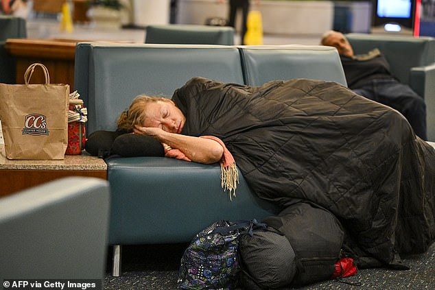 Travellers sleep on chairs at Orlando International Airport in Orlando, Florida on October 30, 2025. Flights at Orlando International Airport faced major delays on October 30, after the Federal Aviation Administration (FAA) said the airport had no certified air-traffic controllers in its tower, forcing arrivals to be halted or severely delayed amid the ongoing US government shutdown. Air traffic controllers -- seen as "essential" public servants -- are kept at work during government shutdowns, but higher numbers are calling in sick rather than toiling without pay, leading to shortages. (Photo by Miguel J. Rodriguez Carrillo / AFP) (Photo by MIGUEL J. RODRIGUEZ CARRILLO/AFP via Getty Images)