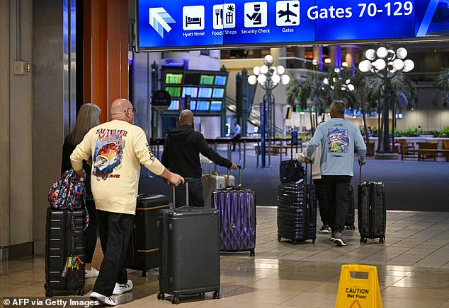 Travellers roll their suitcases as they look for a place to wait at Orlando International Airport in Orlando, Florida on October 30, 2025. Flights at Orlando International Airport faced major delays on October 30, after the Federal Aviation Administration (FAA) said the airport had no certified air-traffic controllers in its tower, forcing arrivals to be halted or severely delayed amid the ongoing US government shutdown. Air traffic controllers -- seen as "essential" public servants -- are kept at work during government shutdowns, but higher numbers are calling in sick rather than toiling without pay, leading to shortages. (Photo by Miguel J. Rodriguez Carrillo / AFP) (Photo by MIGUEL J. RODRIGUEZ CARRILLO/AFP via Getty Images)