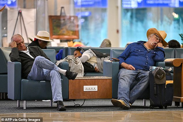 Travellers sleep on chairs at Orlando International Airport in Orlando, Florida on October 30, 2025. Flights at Orlando International Airport faced major delays on October 30, after the Federal Aviation Administration (FAA) said the airport had no certified air-traffic controllers in its tower, forcing arrivals to be halted or severely delayed amid the ongoing US government shutdown. Air traffic controllers -- seen as "essential" public servants -- are kept at work during government shutdowns, but higher numbers are calling in sick rather than toiling without pay, leading to shortages. (Photo by Miguel J. Rodriguez Carrillo / AFP) (Photo by MIGUEL J. RODRIGUEZ CARRILLO/AFP via Getty Images)
