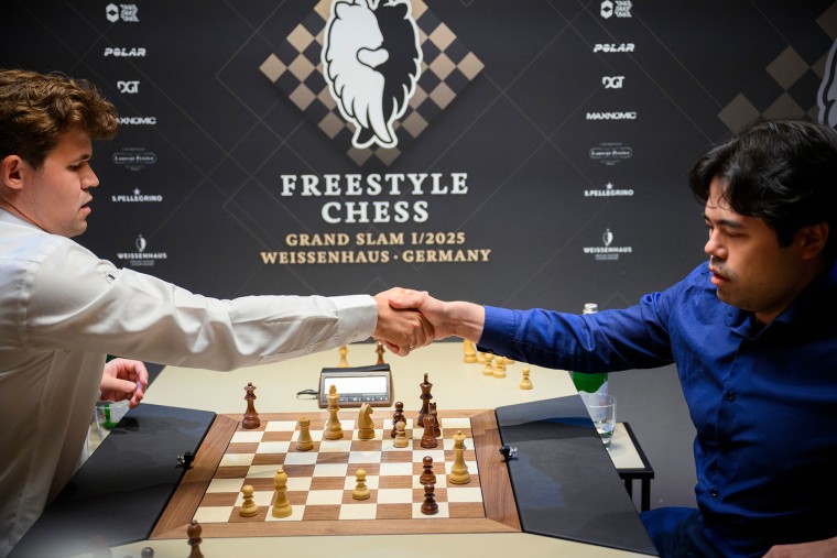 Magnus Carlsen, left, and Hikaru Nakamura shake hands on a chessboard during the Freestyle Chess Grand Slam in Germany on Feb. 7, 2025.