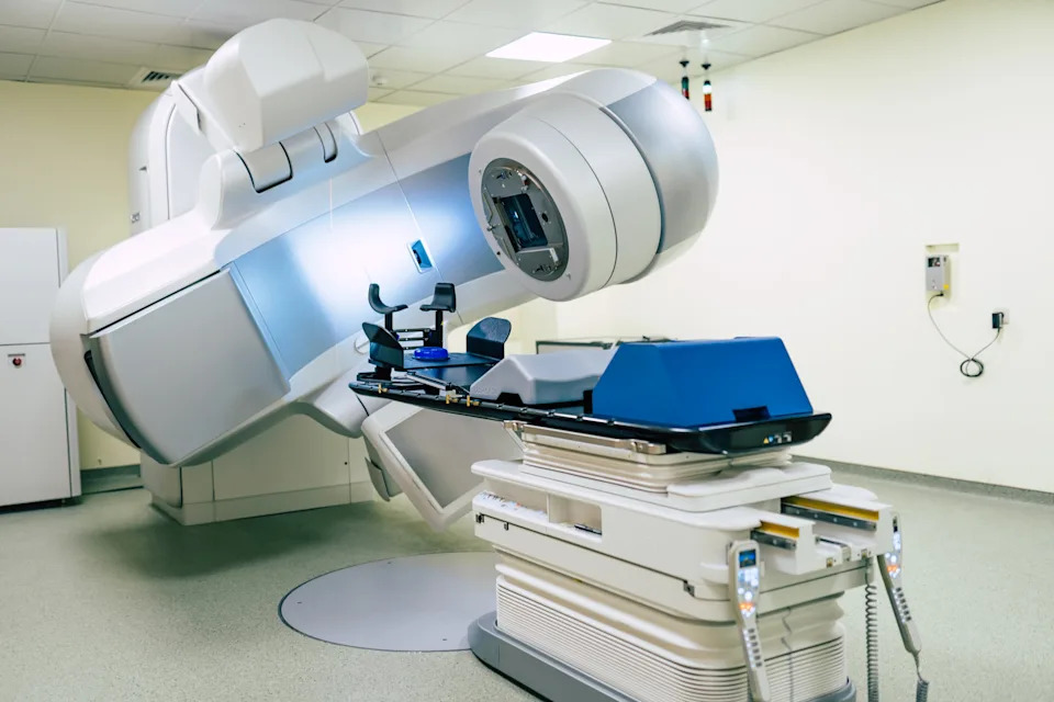 Medical radiation therapy machine in a clinical setting, with a patient table and advanced equipment for cancer treatment