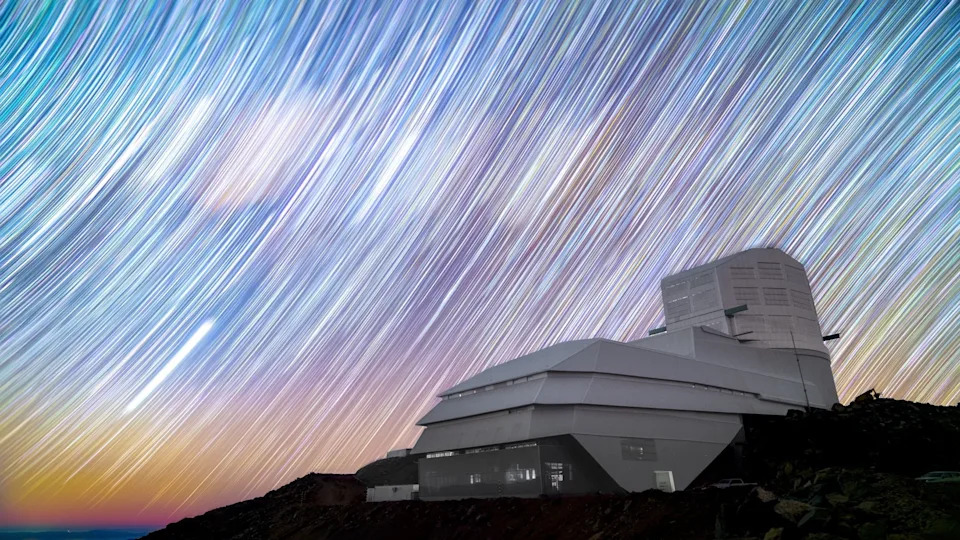 A long-exposure photo of the Vera C. Rubin Observatory in front of a starry sky.