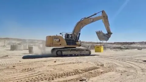 Israeli Defence Ministry via Reuters A screengrab from a handout video shows an Israeli excavator moving yellow barrier blocks to mark the so-called "Yellow Line", in Gaza, released on 20 October 2025