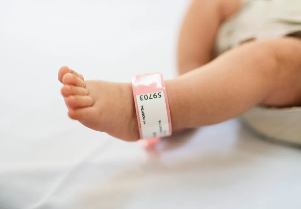 Close-up of a baby's foot wearing a hospital identification band with visible printed numbers