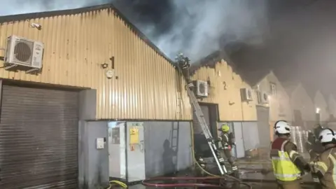PA Media Firefighters tackling a blaze at a Warehouse