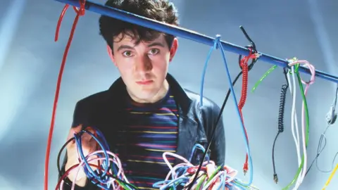 Peter Ashworth Dave Ball holds up an array of multi-coloured patch cables from an early analogue synthesizer