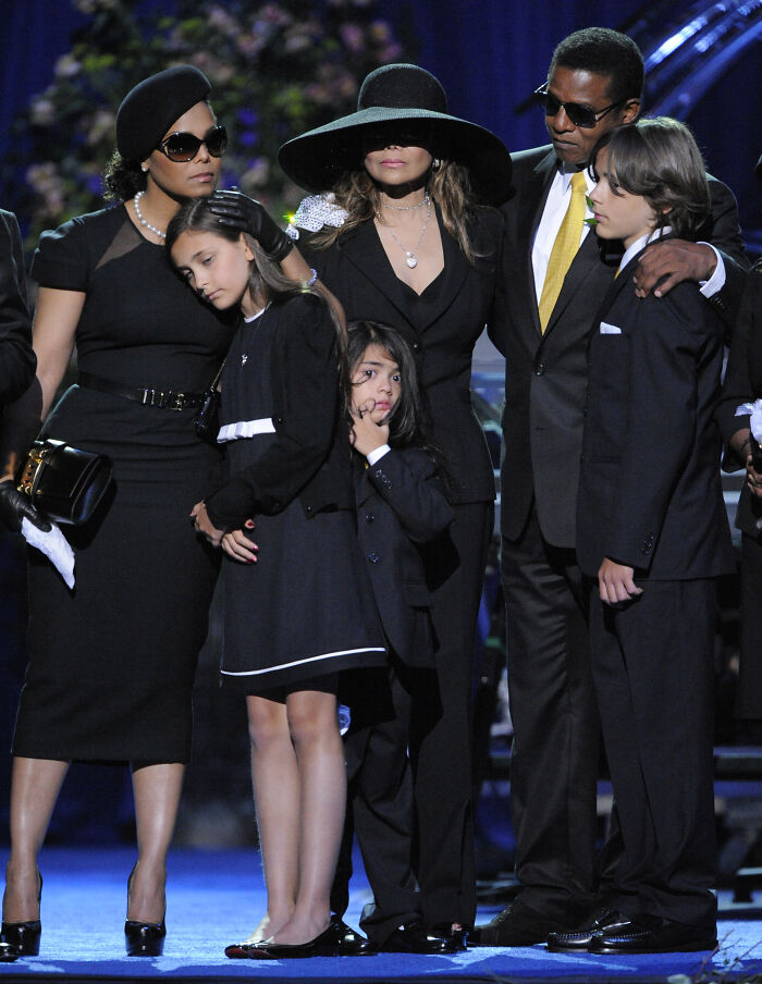 Family dressed in black at a memorial, highlighting Paris Jackson’s shocking claim against Michael Jackson’s estate turmoil.