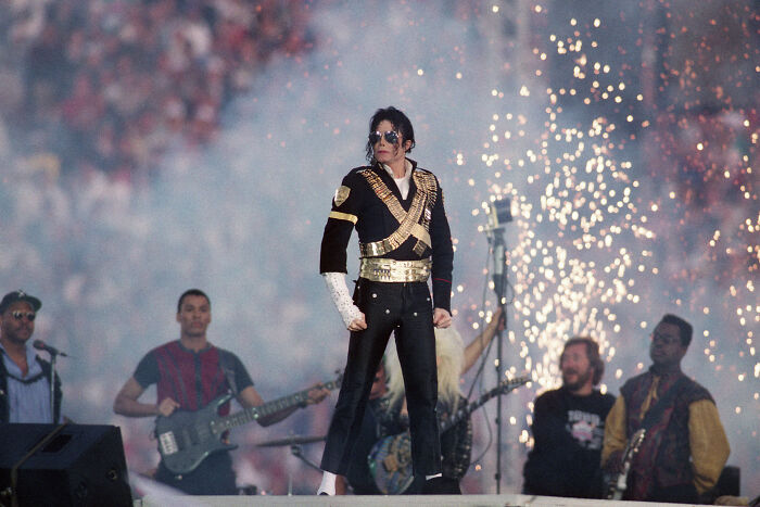 Michael Jackson performing on stage with fireworks in the background during a live concert event.