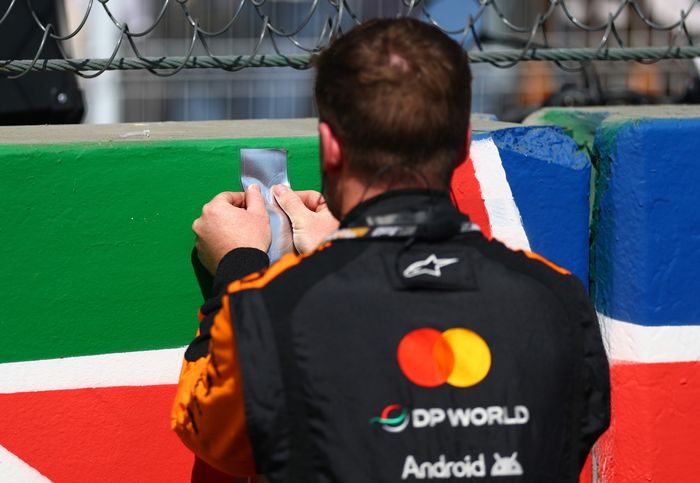 A McLaren team place a sticker on the grid