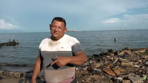 Gustavo Ocando Alex José Luzardo gestures as he stands by the shore of the Venezuelan gulf.