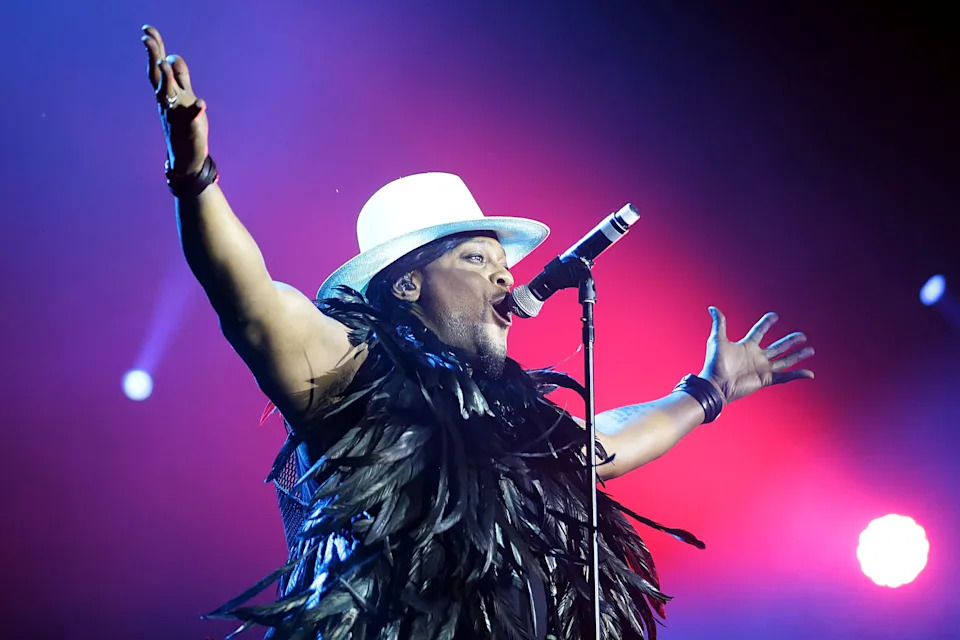 D'Angelo with his arms outstretched, singing into a microphone onstage in Byron Bay, Australia.