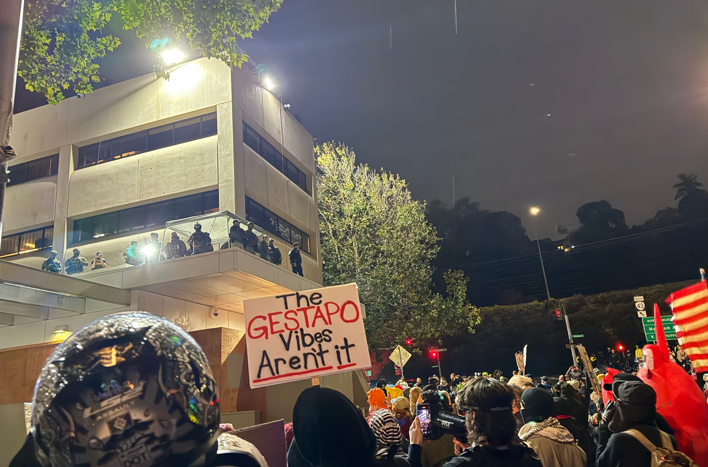Federal law enforcement looms over a crowd at the ICE building in southwest Portland.