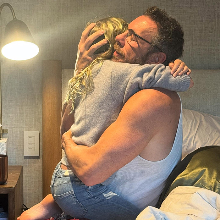 Man in a white tank top hugging a child in a cozy room, highlighting Kristen Bell and Dax Shepard's toxic marriage issues.