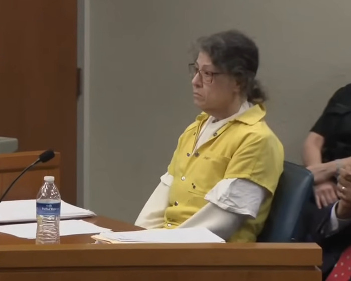 Woman in a yellow prison uniform sitting in a courtroom, related to Netflix’s The Perfect Neighbor disturbing true story.