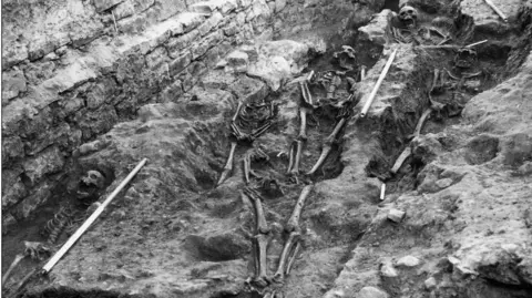 City of Edinburgh Council Three skeletons can been seen exposed in clay in this black and white photograph.