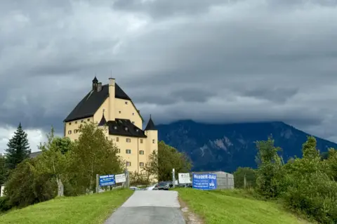 BBC/Bethany Bell Schloss Goldenstein stands on a cloudy day overlooked by the Austrian Alps