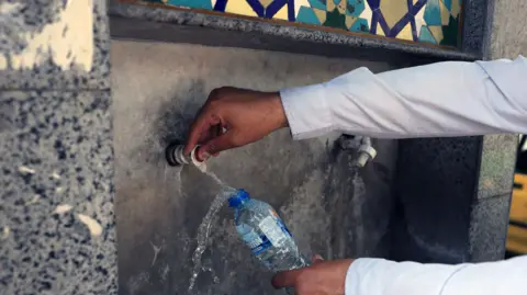 ABEDIN TAHERKENREH/EPA/Shutterstock Someone filling up a water bottle from a water fountain in Tehran