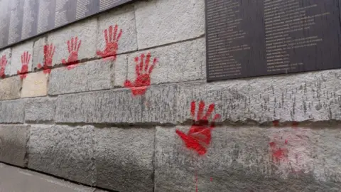 AFP via Getty Images Red hand graffiti seen on the "Wall of the Righteous" (Mur des Justes) outside the Shoah memorial in Paris, on May 14, 2024, after the monument was vandalised overnight, with the president of the Representative Council of French Jewish Institutions (CRIF) denouncing the act as antisemitic.