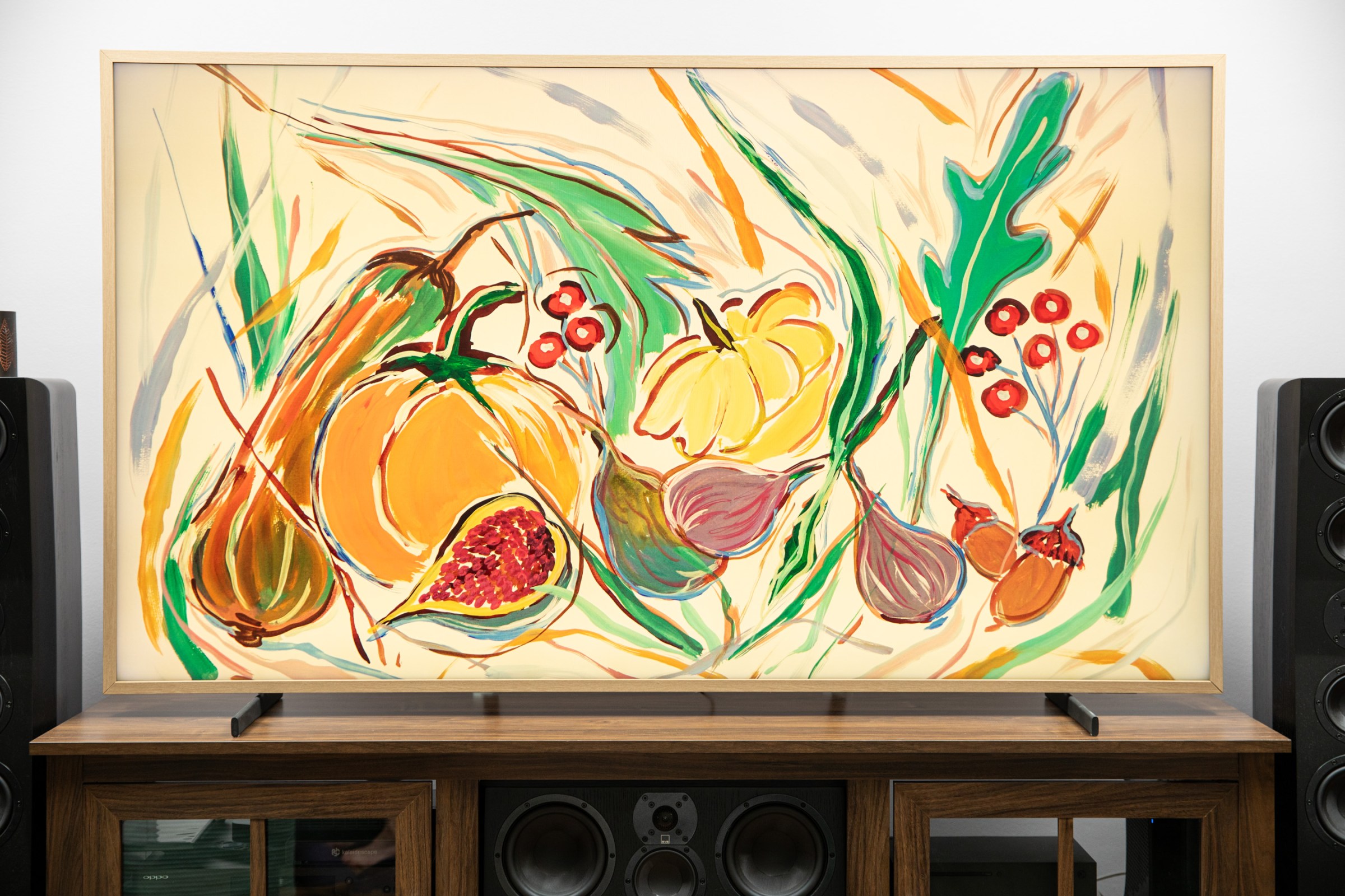 Samsung’s The Frame Pro on a wooden credenza displaying a painting with fall fruits and vegetables.