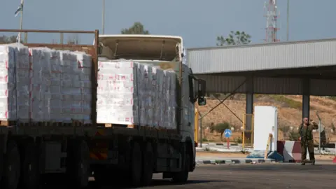 Reuters A lorry carrying aid waits at the Israeli side of the Kerem Shalom border crossing with southern Gaza (20 October 2025)