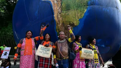 Getty Images Indigenous people pose next to a giant inflatable globe during the "Indigenous People Global March" at the COP30 UN Climate Change Conference in Belem, Para state, Brazil, on November 17, 2025.