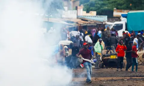 Reuters A protest scene in Tanzania with tear gas in the foreground and a crowd of people looking on
