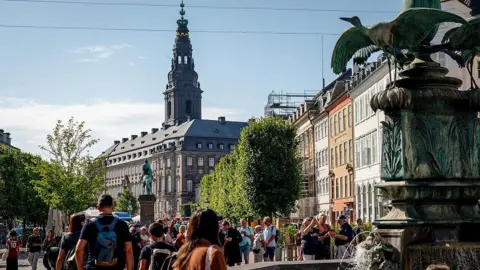 Getty Images Shoppers and tourists mill about next to a fountain in the pedestrianized Stroget shopping street in Copenhagen, Denmark