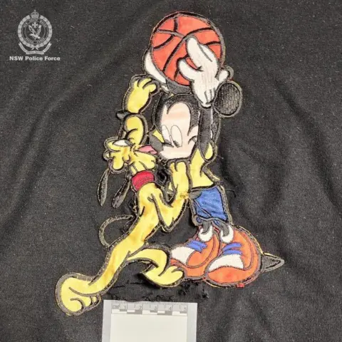 NSW Police A black Mickey Mouse T-shirt with a hole in the middle and an evidence card placed on it