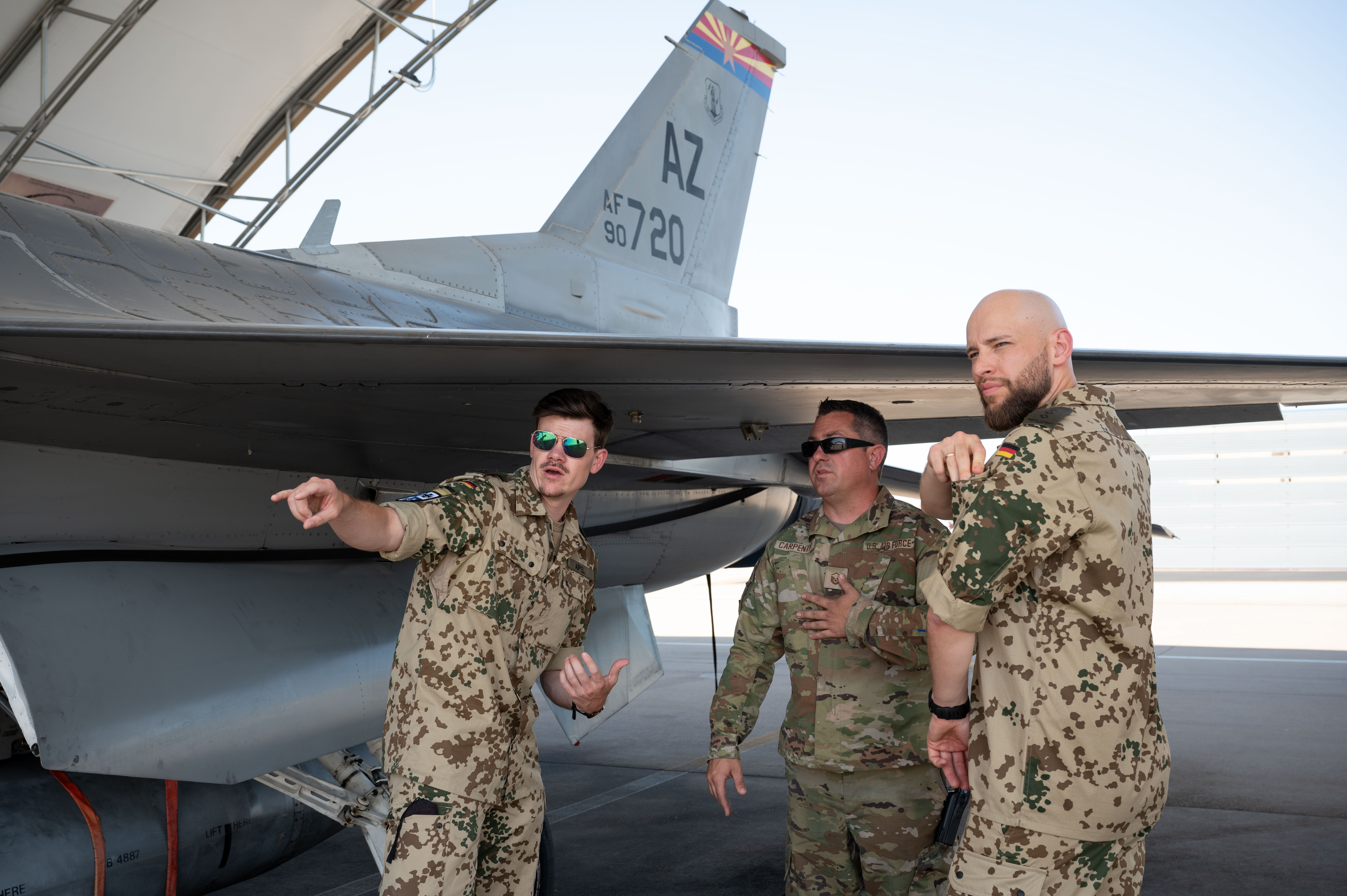 Capt. Christoph Apel, a German servicemember, left, with the Center for Operational Communications, U.S. Air National Guard Master Sgt. Christopher Carpenter, an aircraft mechanic assigned to the 162nd Wing, center, and Capt. Dr. Alexander Witmaier, a German servicemember with the Defense Planning Office, right, gather for an aircraft familiarization tour during their Military Reserve Exchange Program visit to Morris Air National Guard Base, Ariz., June 7, 2024. The German servicemembers were given a comprehensive tour of the squadrons and missions supported throughout their two-week visit to the 162nd Wing. (U.S. Air National Guard photo by Senior Airman Guadalupe Beltran)