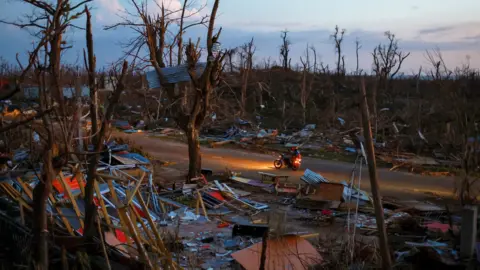 Reuters People ride a bike among debris in an area with no light in the aftermath of Hurricane Melissa in Auchindown, Saint Elizabeth Parish, Jamaica, November 4