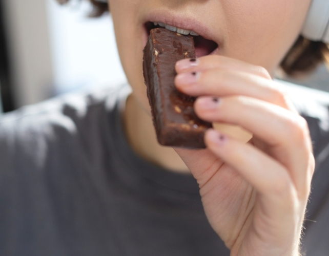 Woman eats a chocolate protein bar 