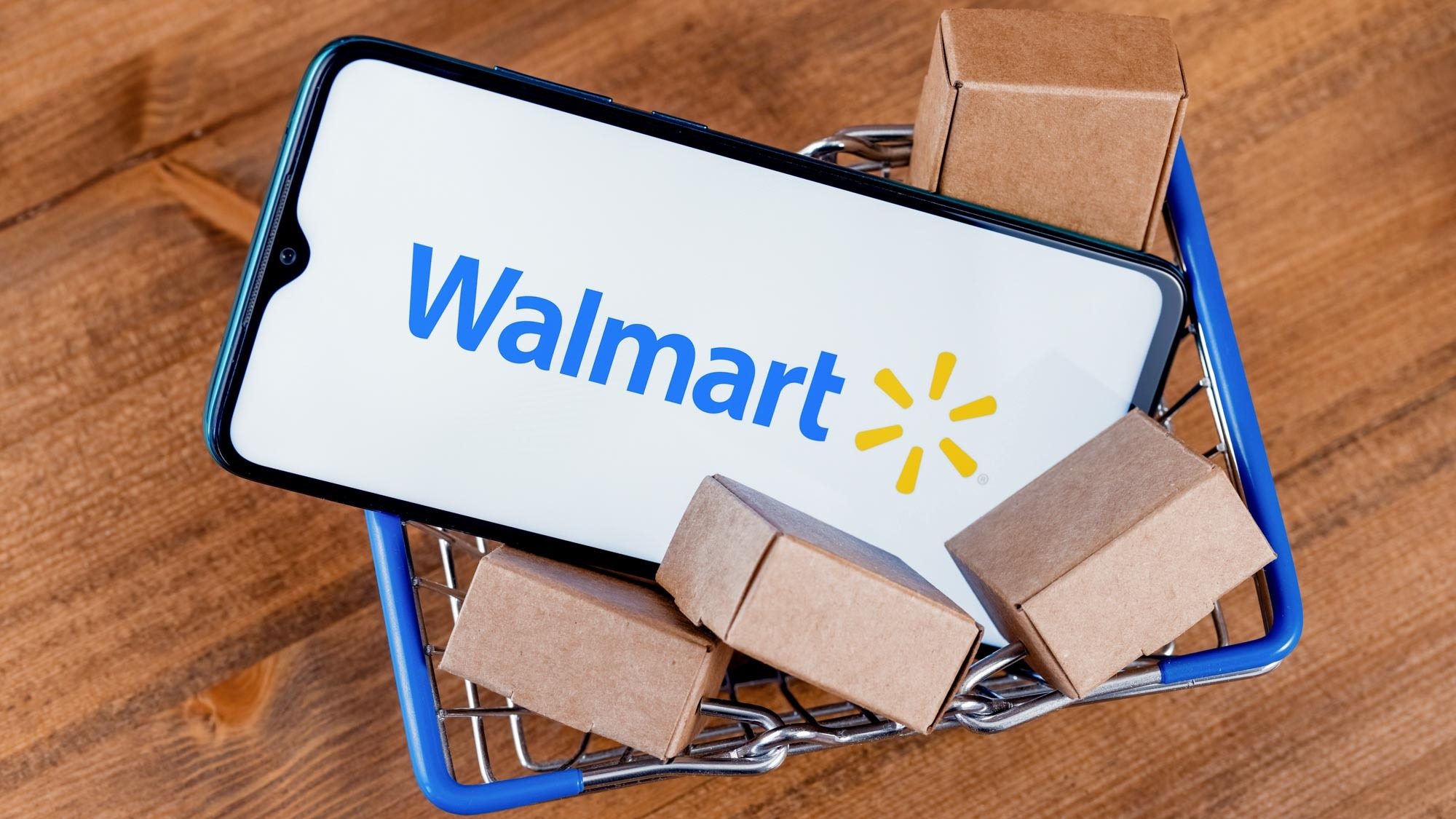 Mini shopping cart holding smartphone with Walmart logo on screen