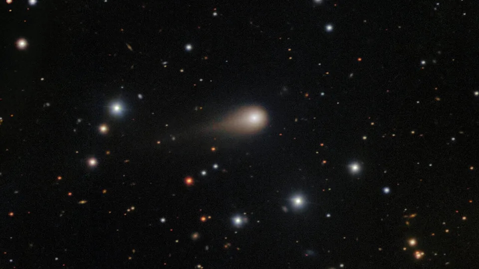 a photo of the comet 3I/ATLAS with its long tail shooting through space