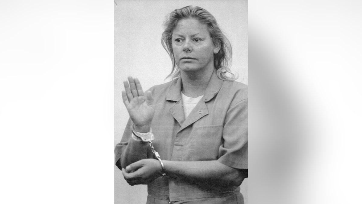 AIleen Wuornos handcuffed in a jumpsuit looking serious.