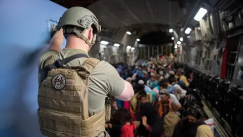 Reuters A US military officer oversees Afghan evacuees on a flight from Kabul in 2021.