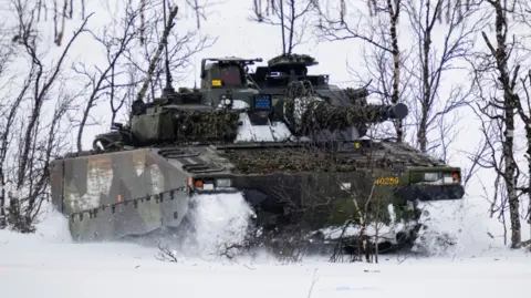 AFP via Getty Images Swedish soldiers of the Finnish-Swedish Division ride the Combat Vehicle 90 (CV90)