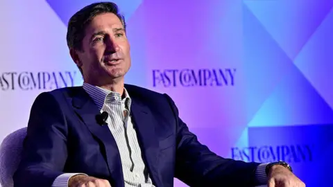 Getty Images for Fast Company A man wearing a blue suit speaks on stage.