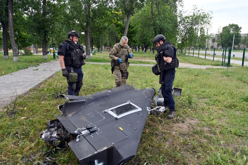 Ukrainian explosives experts and police officers examine parts of a Shahed 136 military drone following an air attack in Kharkiv on June 4, 2025.