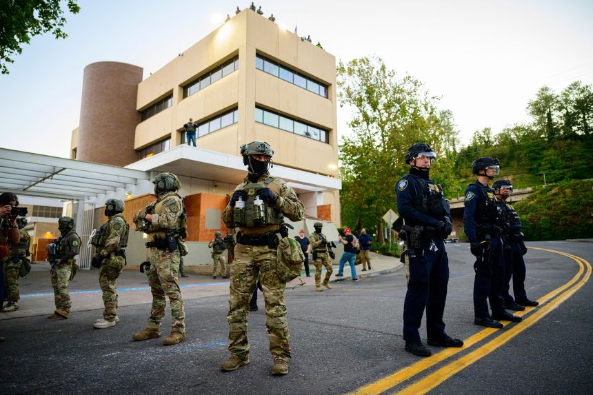 Federal agents, including members of the Department of Homeland Security, ICE, and others, stand guard outside an Immigration and Customs Enforcement facility in downtown Portland, Oregon, on October 6.