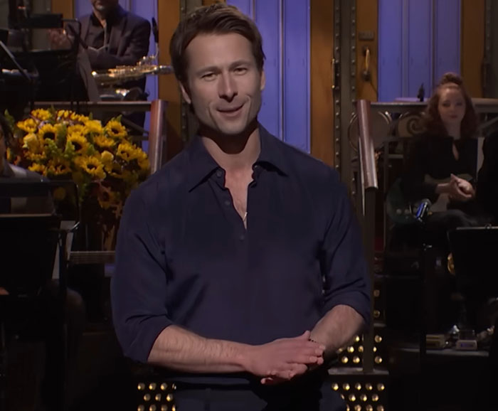 Glenn Powell on stage at SNL, speaking emotionally about flying UPS driver and sharing his dream story. Glenn Powell on stage at SNL, speaking emotionally about flying UPS driver and sharing his dream story.