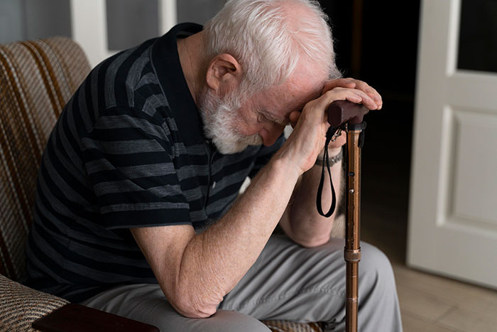 Elderly man resting head on hands over a walking cane, illustrating mysteries about the human body science hasn't explained.