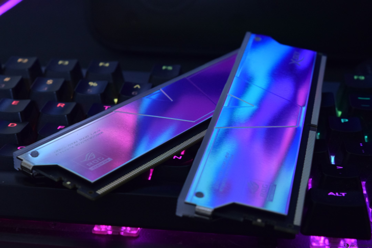 Two ASUS ROG memory modules with RGB lighting effects placed on a backlit mechanical keyboard.