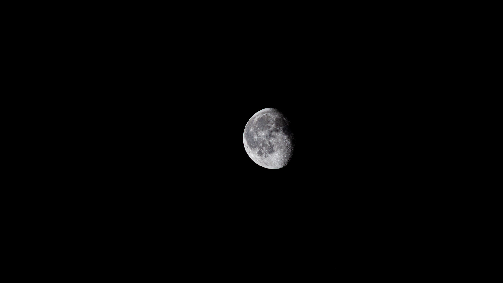 A small waning gibbous moon in the night sky with lunar seas and craters visible.