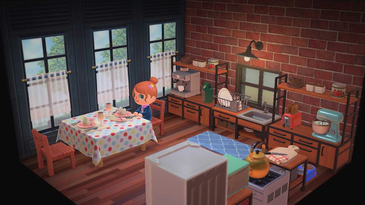 An Animal Crossing character sitting inside her house at a kitchen table. There’s a mixer and a toaster on a shelf to the right, and a coffee maker with coffee on a shelf to the left.