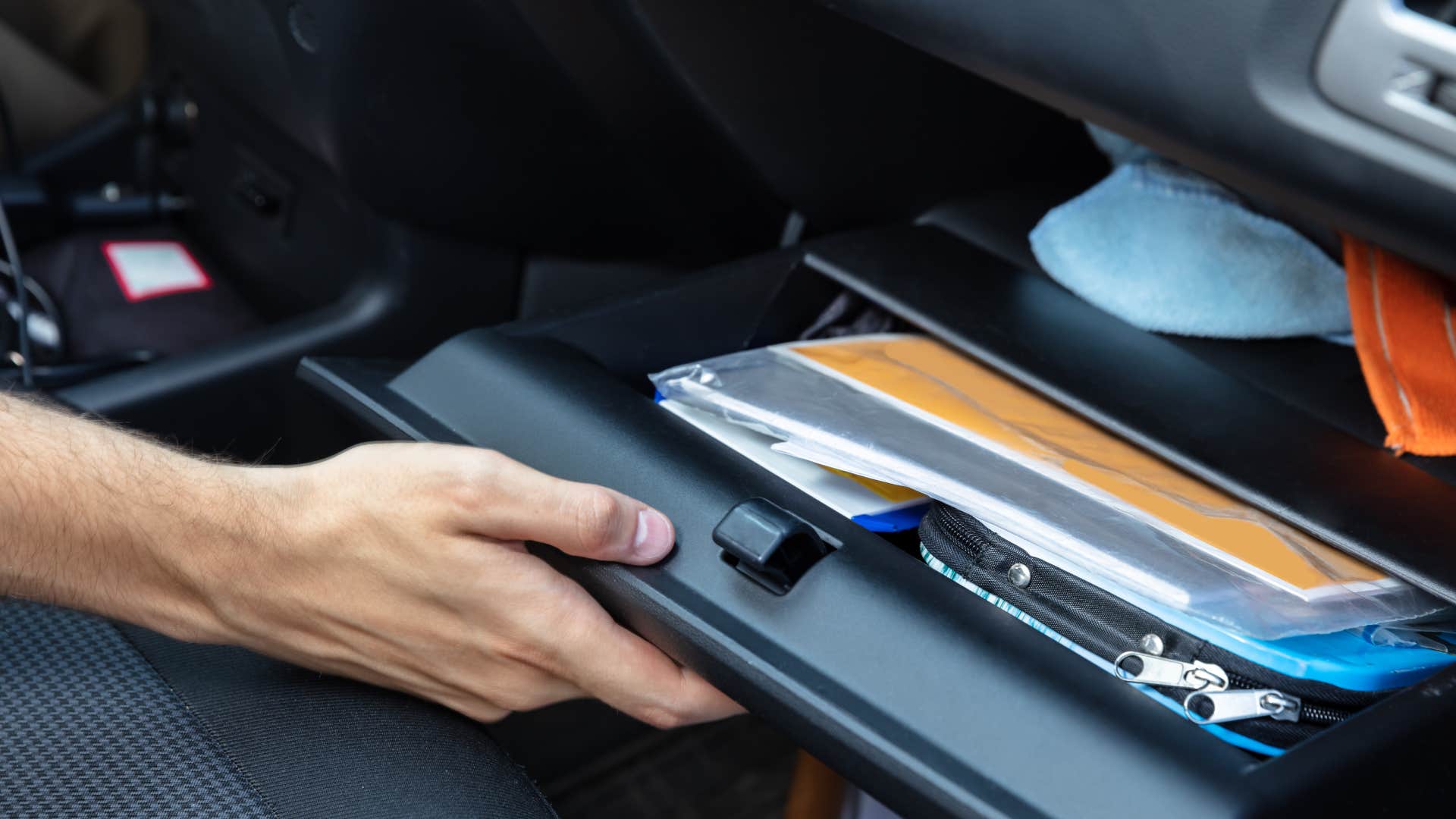 person opening glovebox with unopened mail