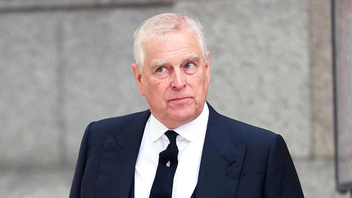 Prince Andrew looking perplexed in a dark suit and matching tie.